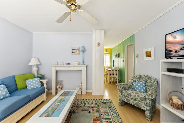 living room with ornamental molding, ceiling fan, and light wood-type flooring