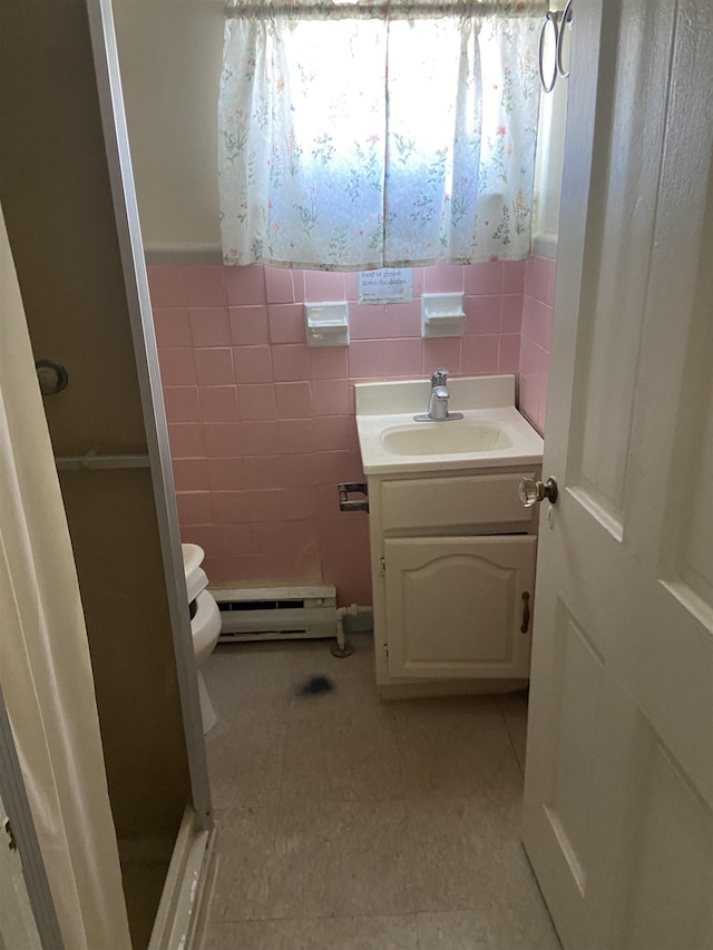 bathroom featuring vanity, toilet, a baseboard heating unit, tile walls, and a stall shower