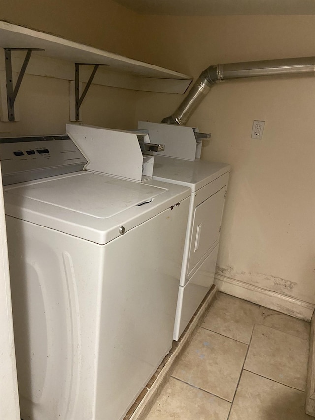 laundry room featuring light tile patterned floors, separate washer and dryer, laundry area, and baseboards
