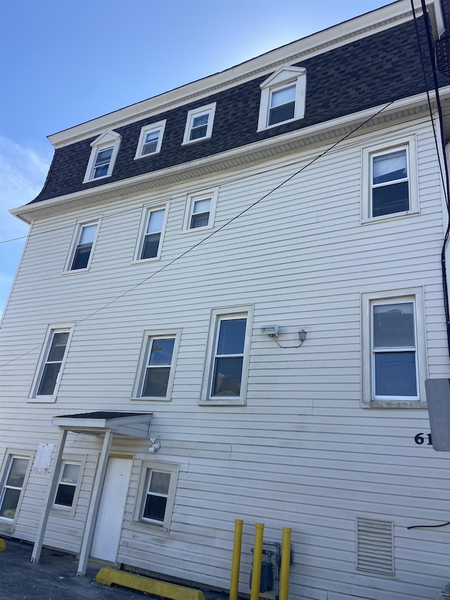 rear view of property with roof with shingles and mansard roof