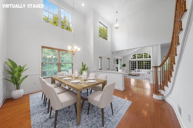 dining room featuring wood-type flooring, a towering ceiling, and a chandelier