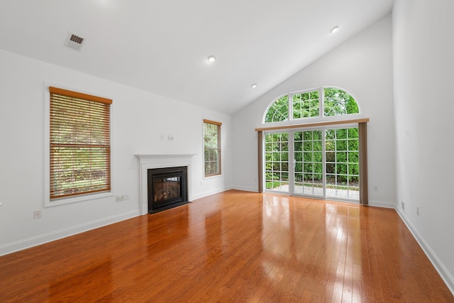 unfurnished living room with light wood-type flooring and high vaulted ceiling