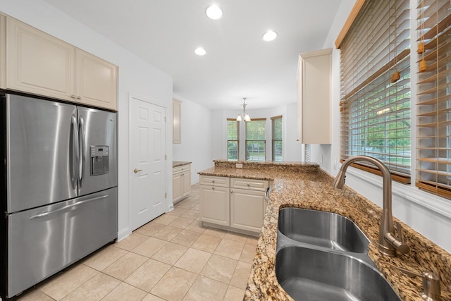 kitchen with stone counters, stainless steel fridge with ice dispenser, sink, and pendant lighting