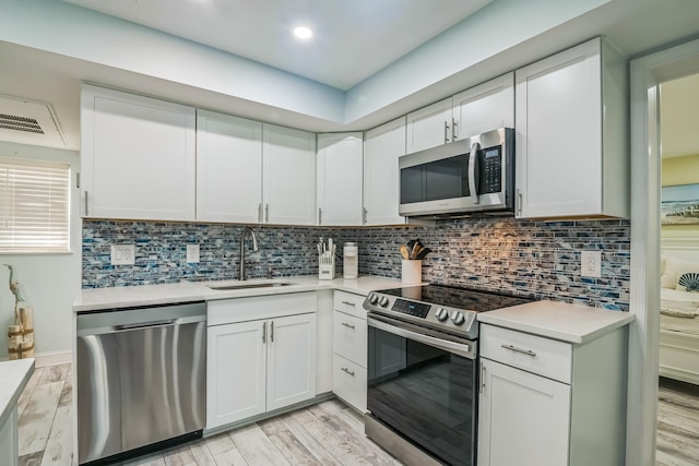 405 Ocean Ave Unit 110, North Wildwood, NJ 08260 - kitchen with appliances with stainless steel finishes, light countertops, backsplash, white cabinets, and light wood-style floors