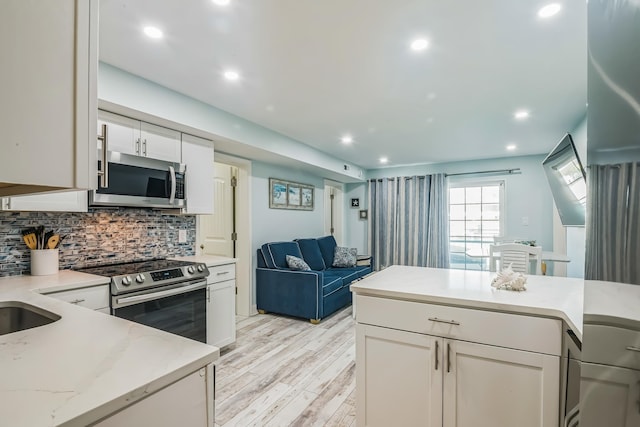 405 Ocean Ave Unit 110, North Wildwood, NJ 08260 - kitchen featuring appliances with stainless steel finishes, light wood finished floors, open floor plan, decorative backsplash, and white cabinetry