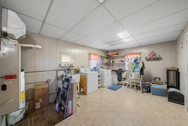 basement featuring washing machine and dryer, a paneled ceiling, and wooden walls