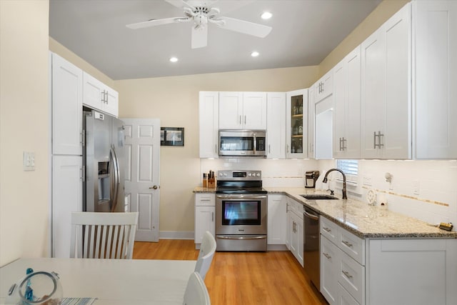 kitchen featuring light wood-type flooring, stainless steel appliances, ceiling fan, sink, and white cabinets