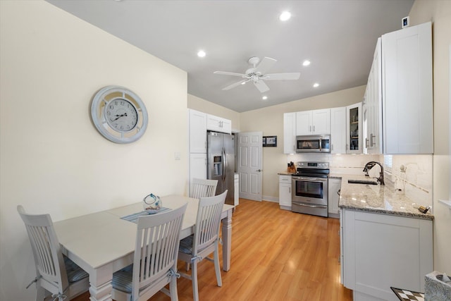 kitchen with sink, ceiling fan, appliances with stainless steel finishes, light stone counters, and white cabinetry