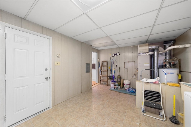 basement with wood walls, a drop ceiling, and gas water heater