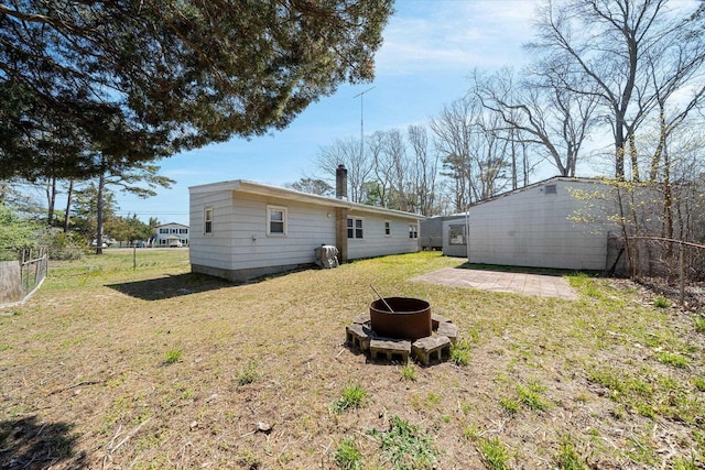 back of property with a yard, a patio, and an outdoor fire pit