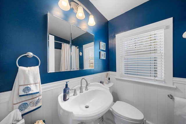 bathroom featuring a shower with shower curtain, toilet, and sink