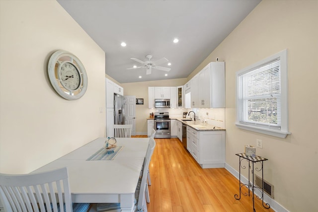 kitchen with lofted ceiling, white cabinets, sink, ceiling fan, and appliances with stainless steel finishes