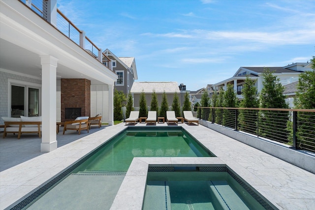 view of pool with an in ground hot tub, an outdoor living space with a fireplace, and a patio area