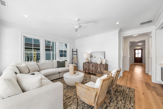 living room with ornamental molding, light hardwood / wood-style floors, and ceiling fan