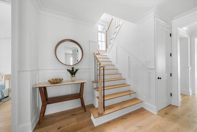 staircase with hardwood / wood-style floors and ornamental molding