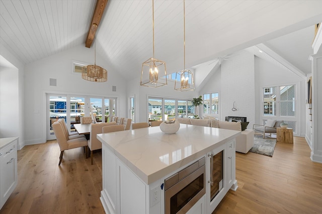 kitchen with stainless steel microwave, decorative light fixtures, a brick fireplace, and white cabinets