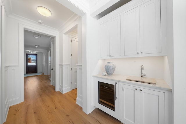 bar with white cabinetry, sink, wine cooler, and light hardwood / wood-style floors