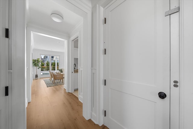 hallway with ornamental molding and light wood-type flooring