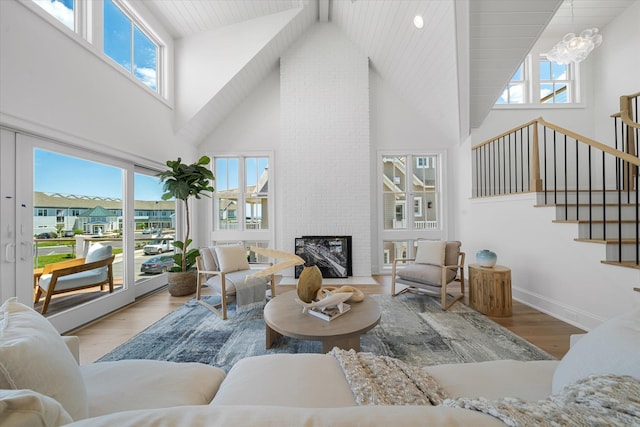 living room featuring a healthy amount of sunlight, hardwood / wood-style floors, high vaulted ceiling, and a brick fireplace