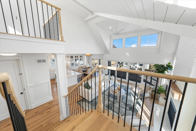 staircase featuring ornate columns, high vaulted ceiling, wood-type flooring, ceiling fan, and beam ceiling