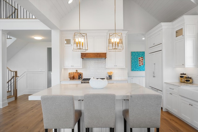 kitchen with white cabinetry, light stone counters, and decorative light fixtures