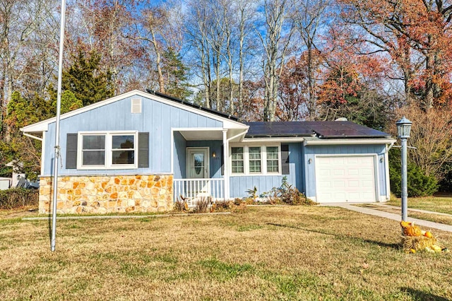 ranch-style home with solar panels, a garage, covered porch, and a front yard