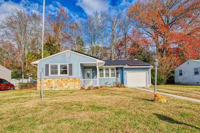 view of front facade featuring covered porch, a front lawn, a garage, and solar panels