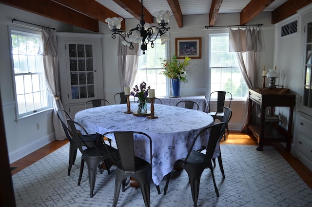 dining area with beamed ceiling, a chandelier, and light wood-type flooring