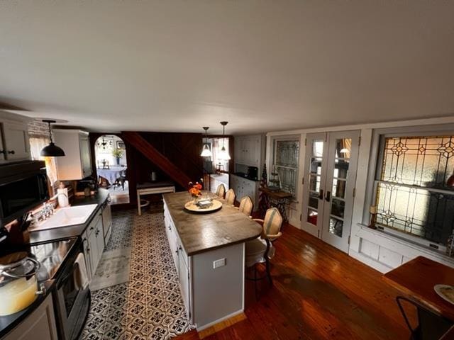 kitchen with a center island, french doors, hanging light fixtures, stainless steel range with electric cooktop, and white cabinets