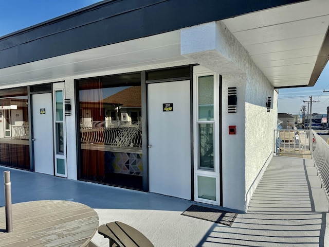 property entrance with a balcony and stucco siding