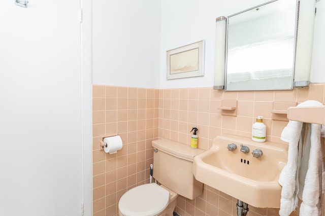 bathroom with sink, tile walls, and toilet