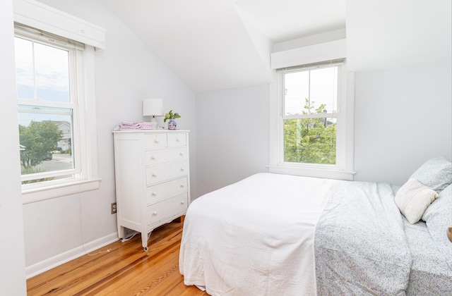 bedroom with vaulted ceiling and light hardwood / wood-style flooring