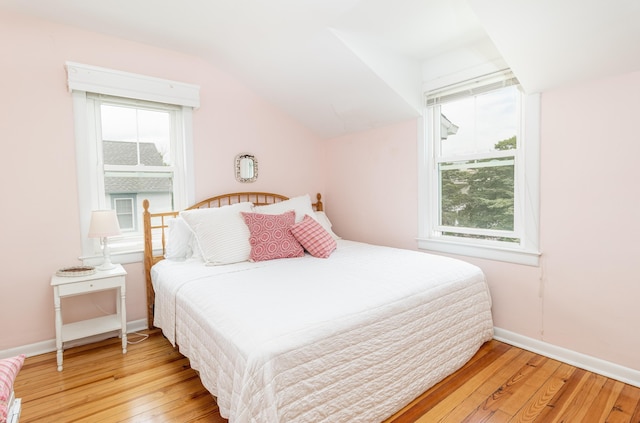 bedroom with light wood-type flooring, multiple windows, and lofted ceiling