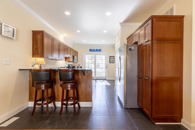 kitchen with ornamental molding, appliances with stainless steel finishes, a peninsula, and dark tile patterned flooring