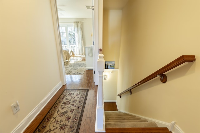 staircase with visible vents, baseboards, and wood-type flooring