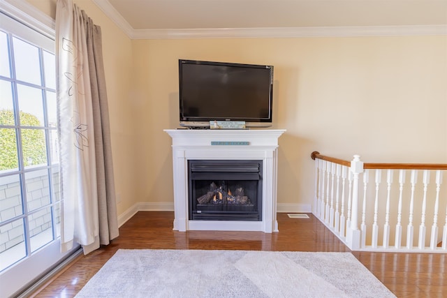 unfurnished living room featuring baseboards, a lit fireplace, wood finished floors, and crown molding