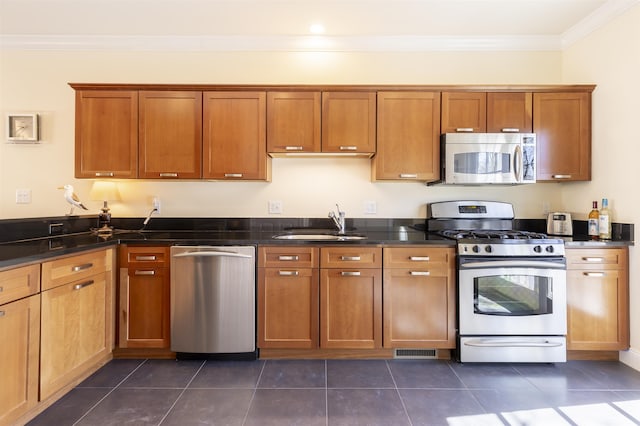 kitchen featuring visible vents, ornamental molding, appliances with stainless steel finishes, brown cabinetry, and a sink