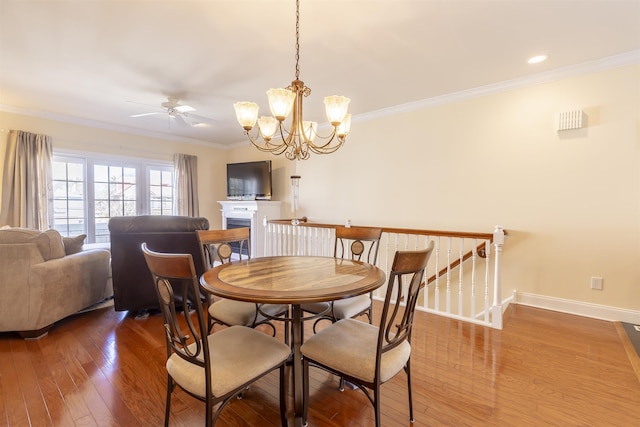 dining space featuring hardwood / wood-style floors, crown molding, a fireplace, and baseboards