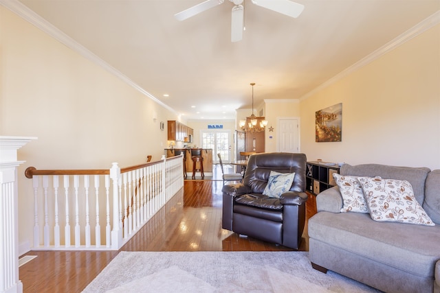 living room with ceiling fan with notable chandelier, ornamental molding, and hardwood / wood-style flooring