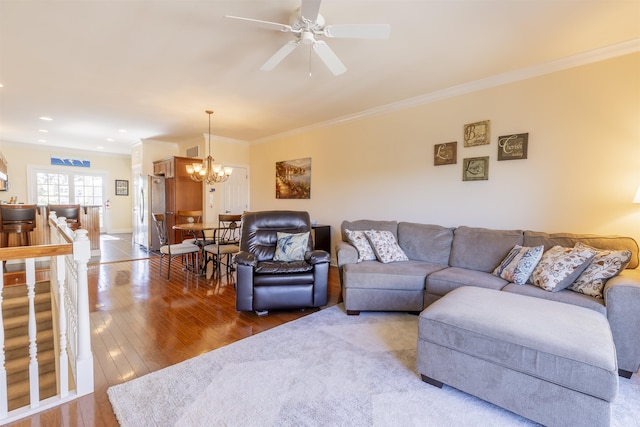 living area with visible vents, ornamental molding, ceiling fan with notable chandelier, and hardwood / wood-style flooring