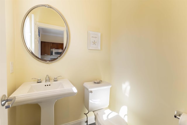 bathroom featuring toilet, baseboards, and a sink