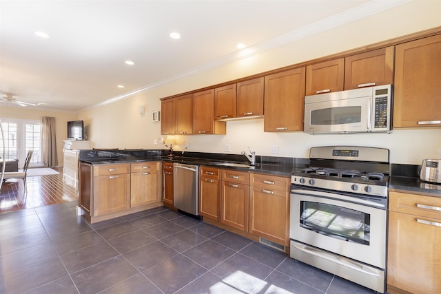 kitchen featuring a peninsula, a sink, ornamental molding, appliances with stainless steel finishes, and brown cabinets