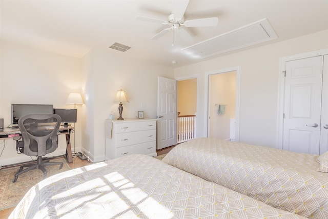 bedroom featuring a ceiling fan, wood finished floors, visible vents, baseboards, and attic access