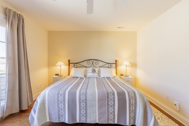 bedroom with wood finished floors, baseboards, visible vents, and ceiling fan