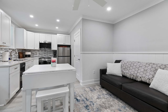 kitchen featuring light wood-type flooring, white cabinetry, crown molding, and stainless steel appliances
