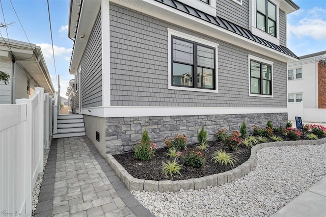 view of property exterior featuring fence and metal roof