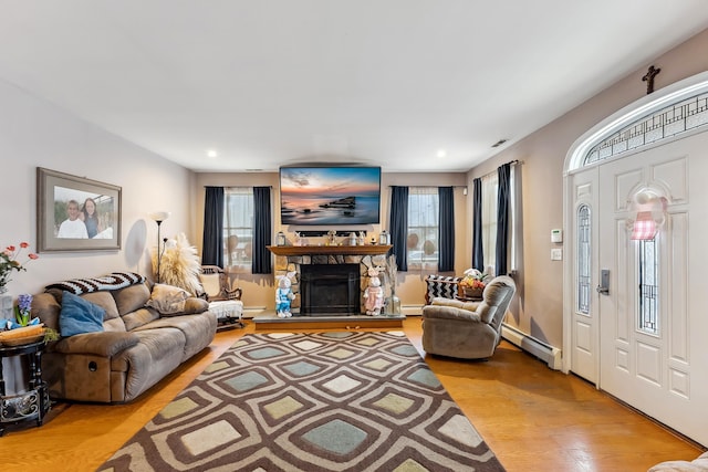 living area featuring baseboard heating, a baseboard radiator, plenty of natural light, and light wood-type flooring