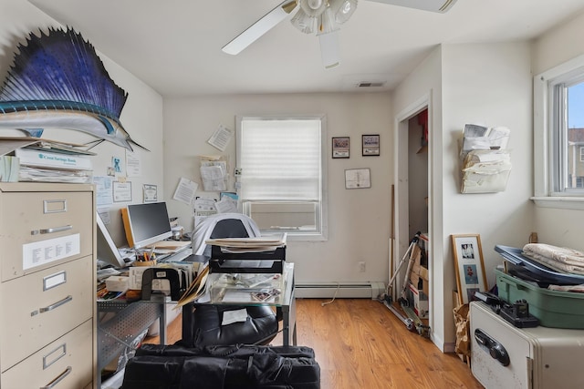 office area with baseboard heating, visible vents, ceiling fan, and light wood-style flooring