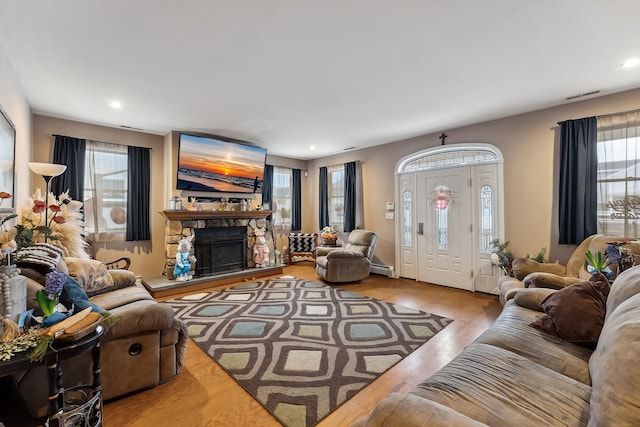 living area featuring a baseboard heating unit, visible vents, recessed lighting, wood finished floors, and a fireplace