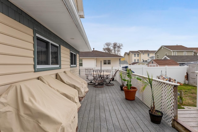 wooden deck featuring a residential view, outdoor dining area, and fence